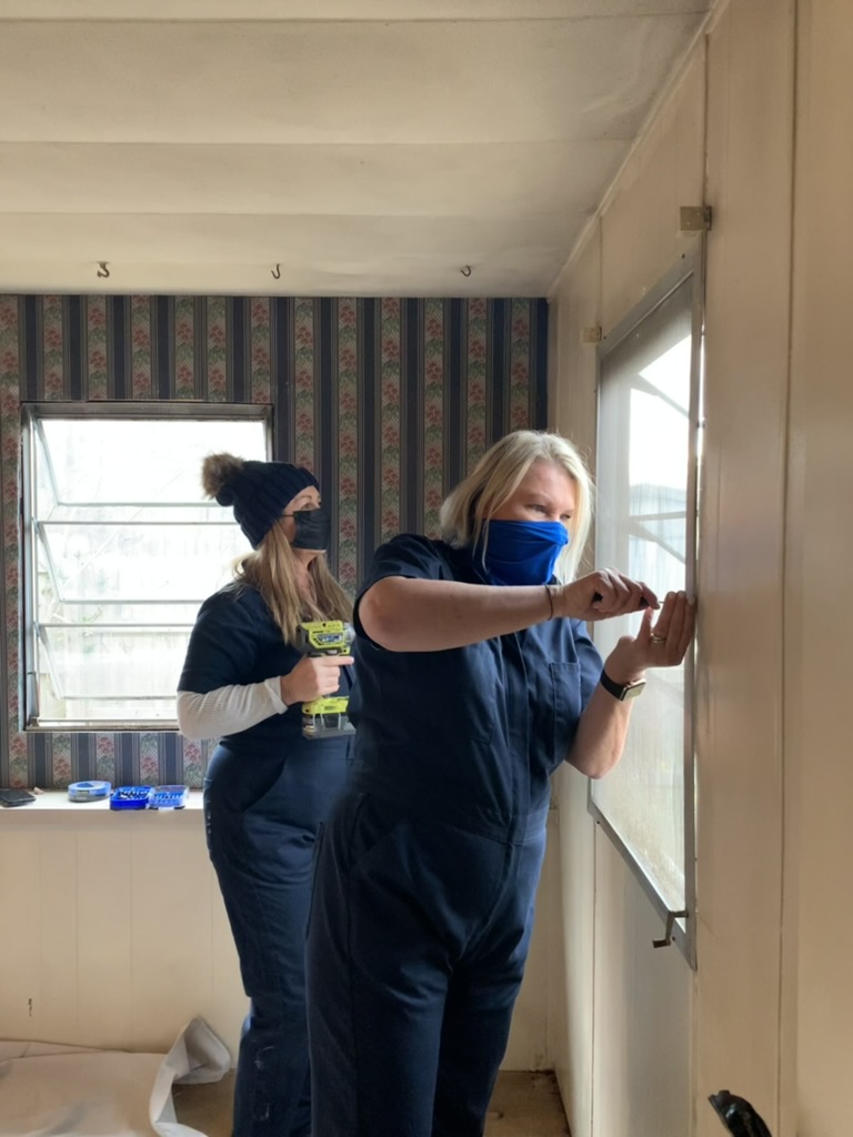 Volunteers working on a bedroom door frame during a one-day Room Redux of Georgia transformation.
