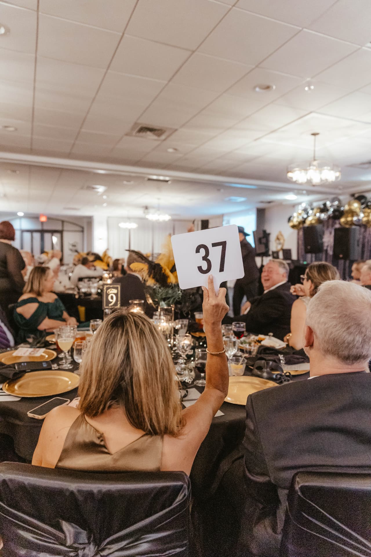 A guest raising her bidder paddle during the live auction.