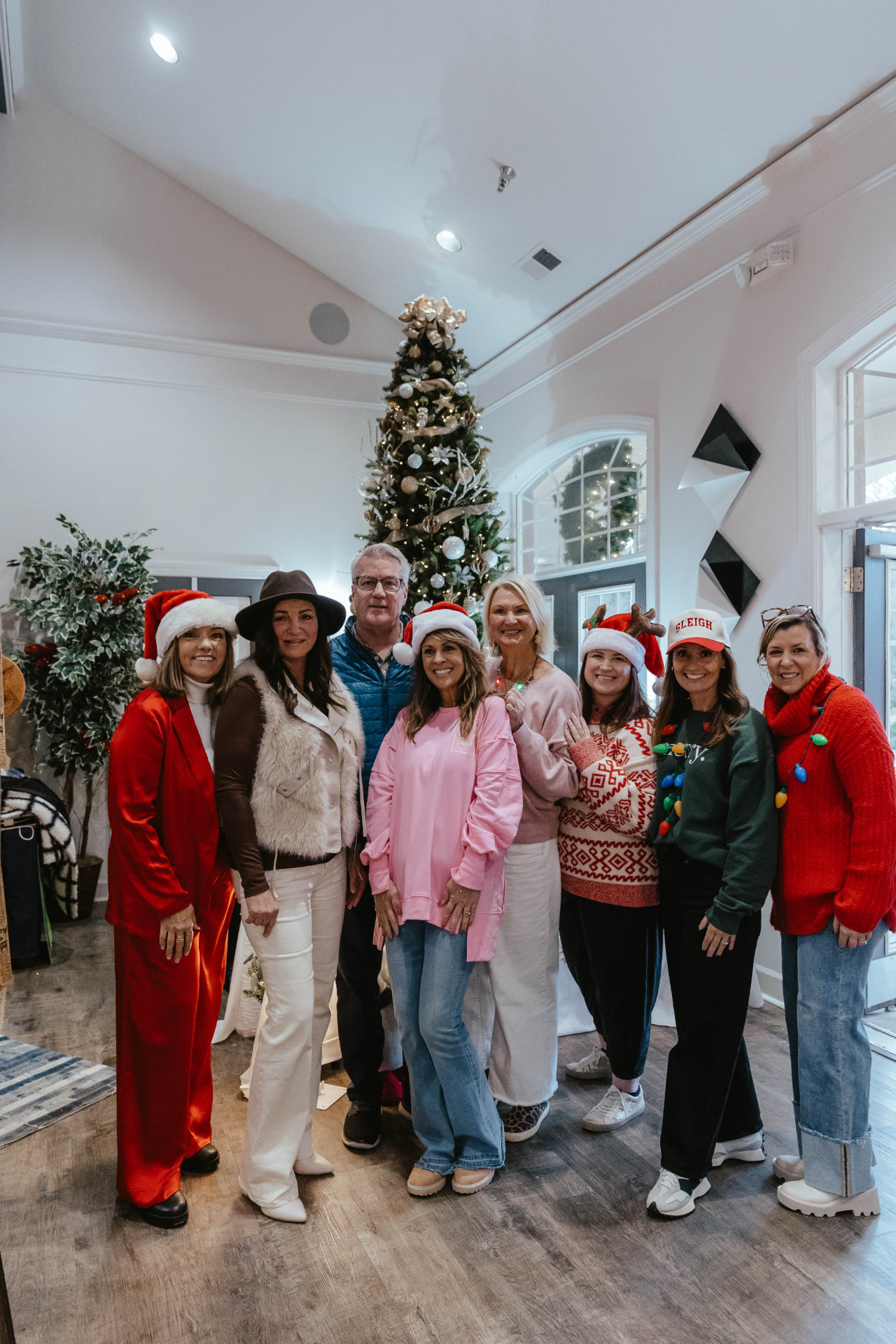 Group gathered in front of a decorated holiday tree at the Sip & Sparkle Vendor Holiday Market.