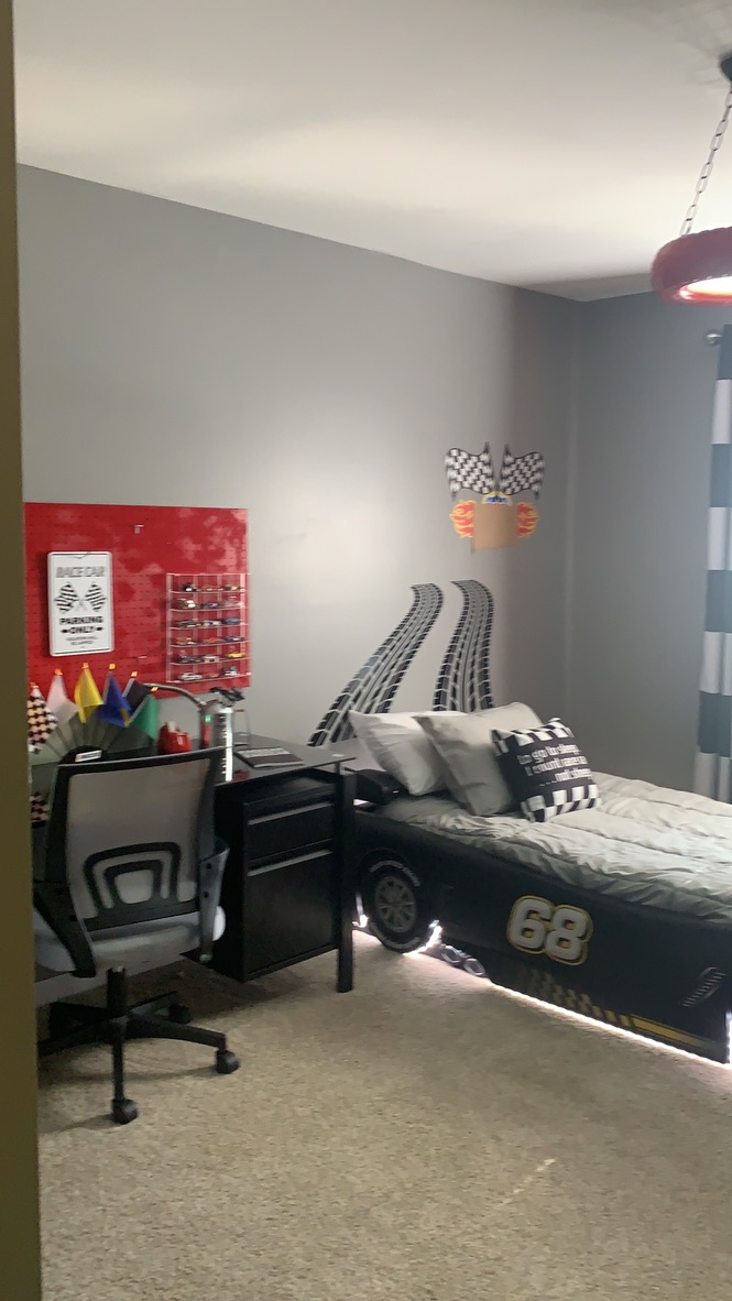 Completed race car themed RRGA bedroom with a car-shaped bed, checkered flag décor and a study desk.