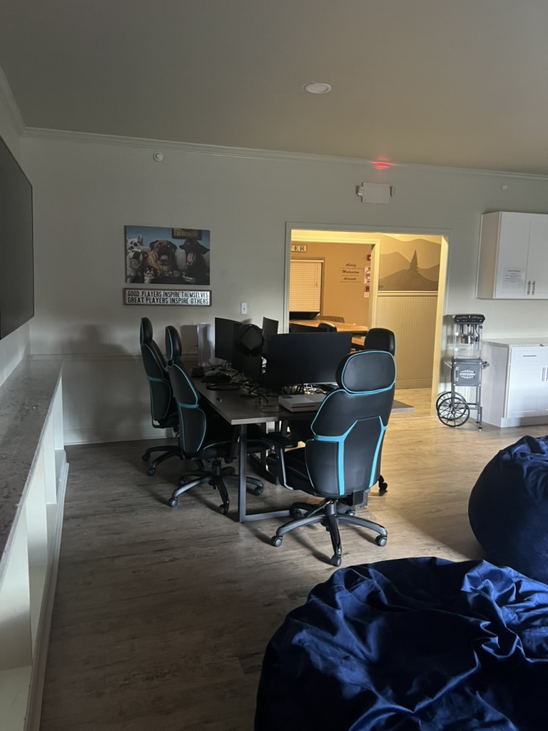 The finished gaming workstation with eight chairs and monitors in the transformed shared living space.