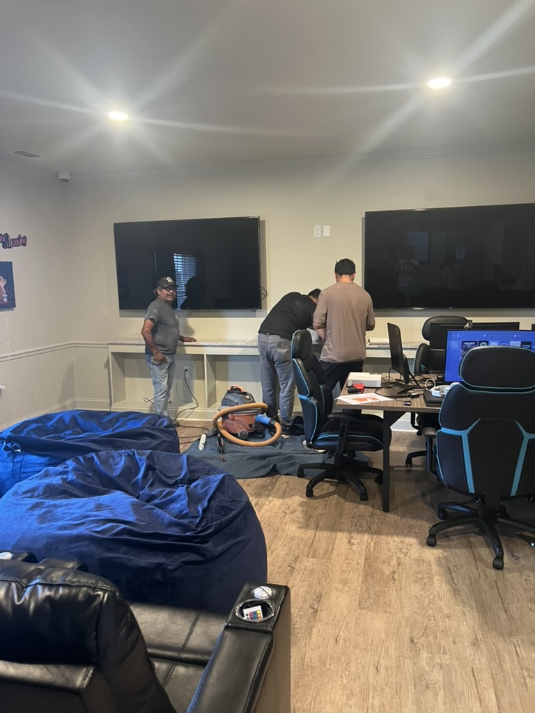 Build day in progress as two large wall-mounted televisions are installed above a new built-in counter.
