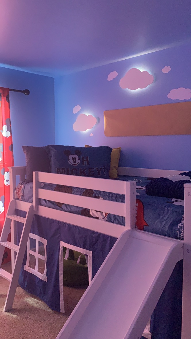 Completed children’s bedroom with colorful lighting and a raised bed.