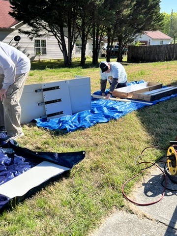 Volunteers preparing bedroom furniture outdoors during a transformation.