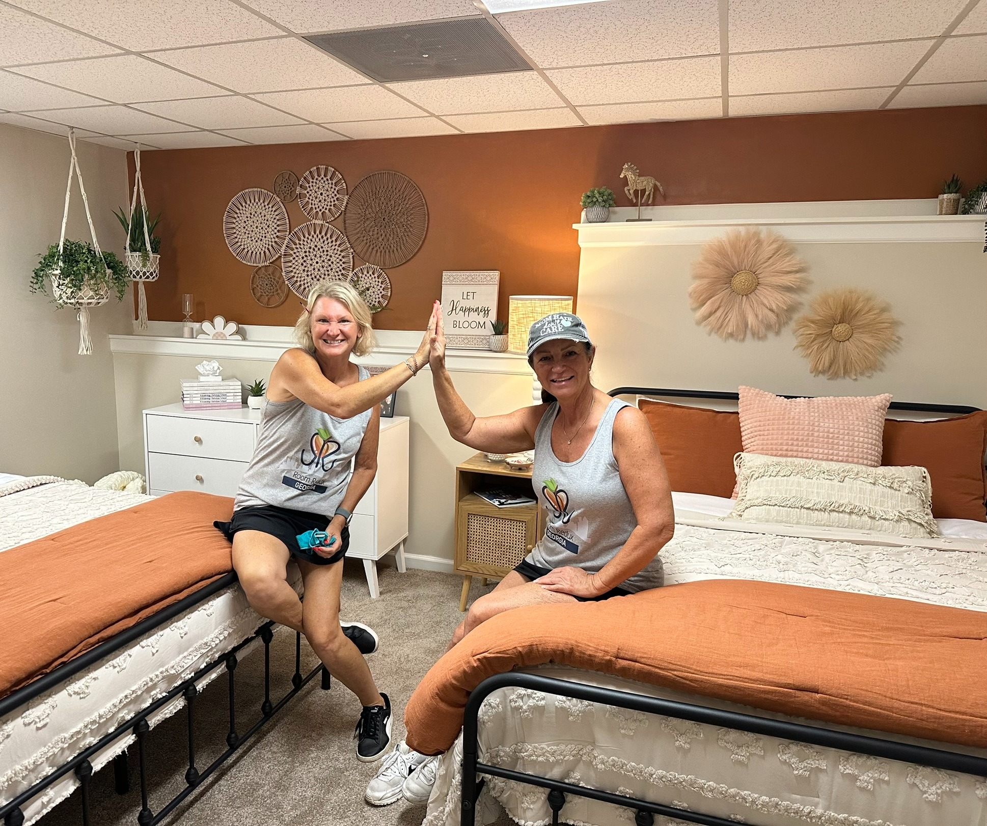 Two RRGA volunteers celebrating inside a completed shared bedroom.