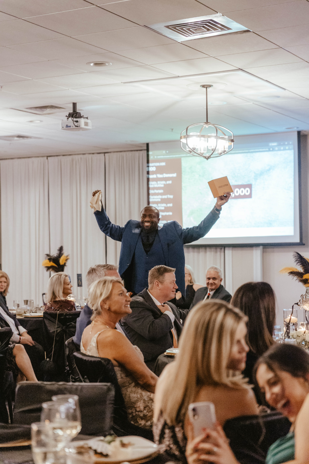 A guest celebrating a winning auction moment beside the presentation screen.