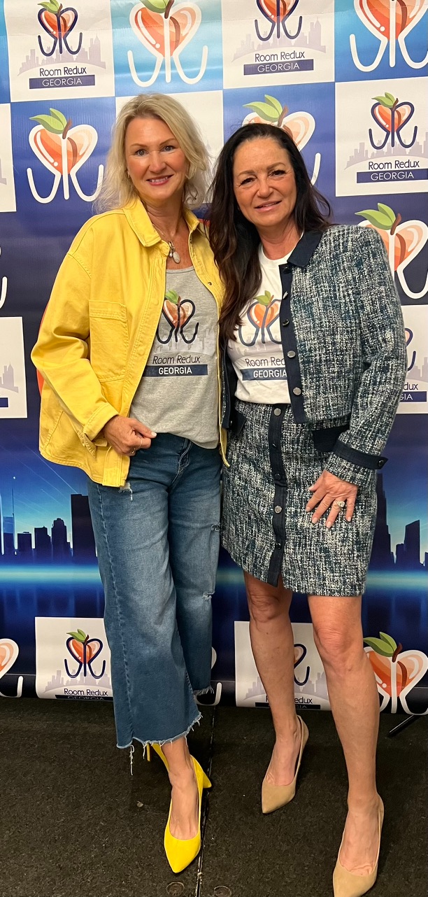 Stephanie Engelerdt and Lisa Lepkofker stand together in Room Redux of Georgia shirts in front of a branded step-and-repeat backdrop.