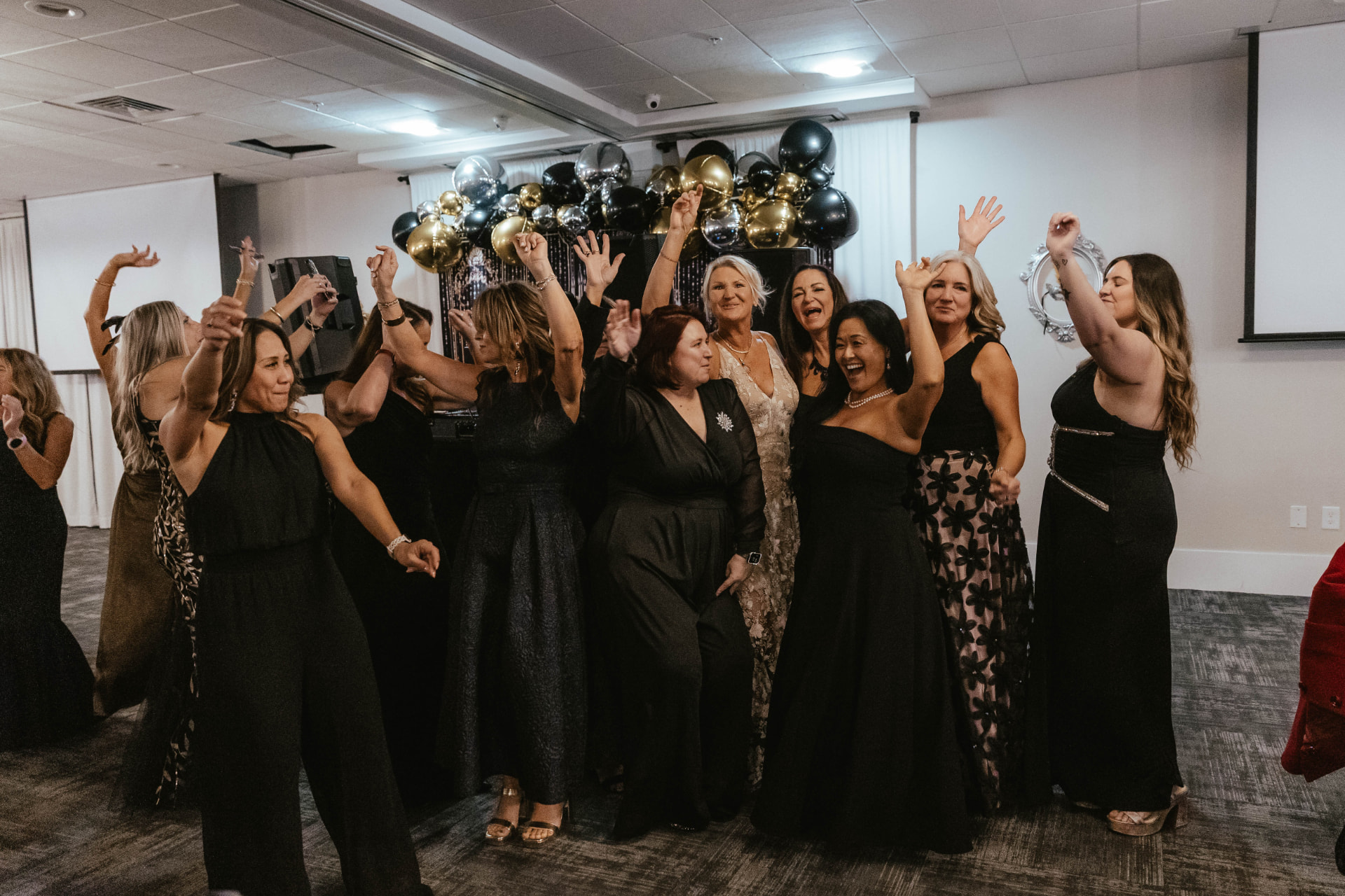 Gala guests dancing in front of a black, gold and silver balloon installation.