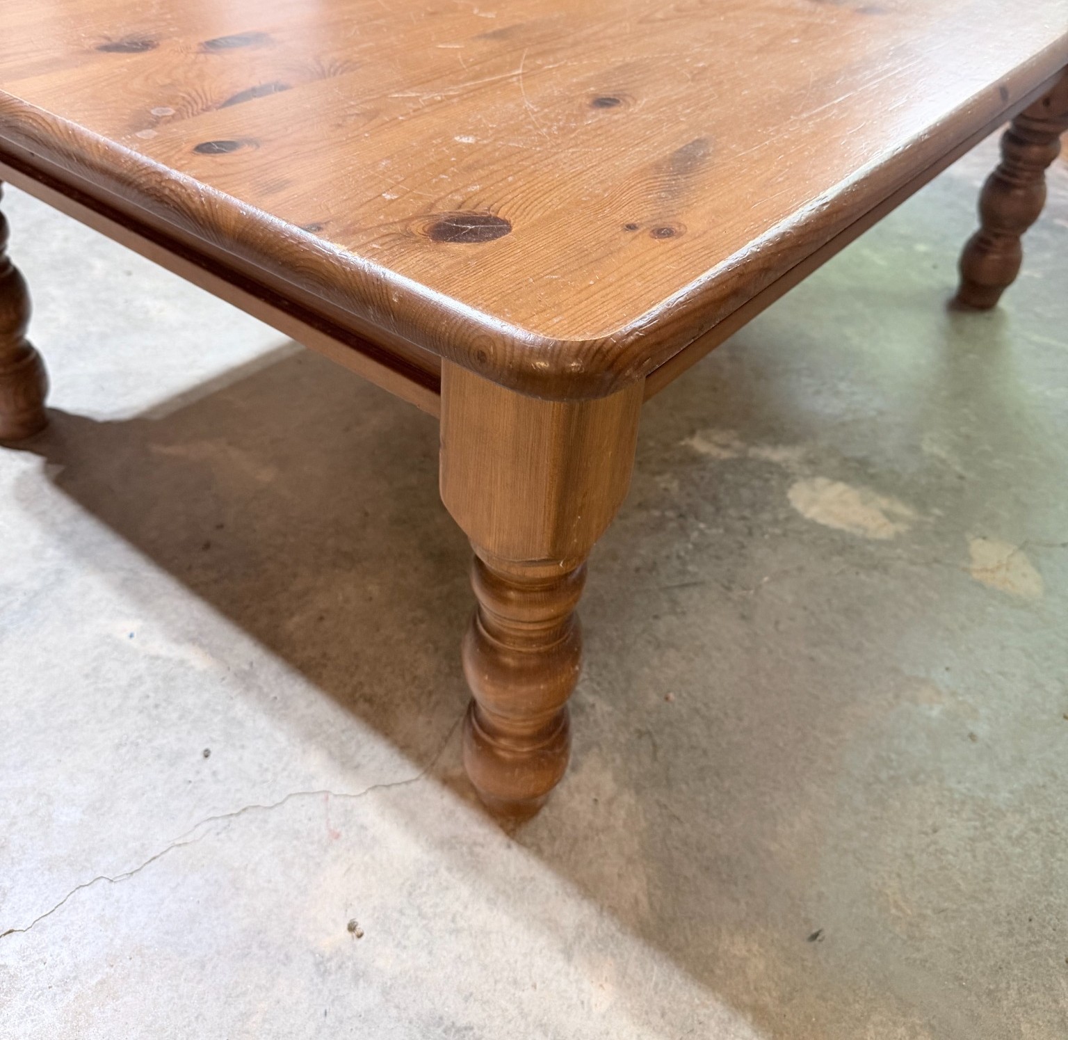 A donated solid wood dining table photographed for resale at the SELL Co. warehouse.