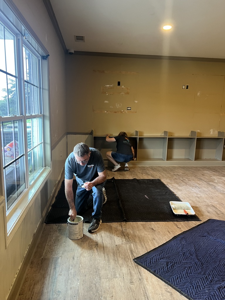 Volunteers patching and painting the walls and built-in shelving early in the build.