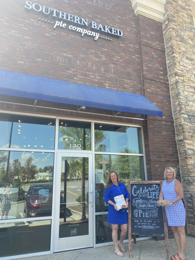 Stephanie Engelerdt and Lisa Lepkofker standing in front of Southern Baked Pie Company with pies.