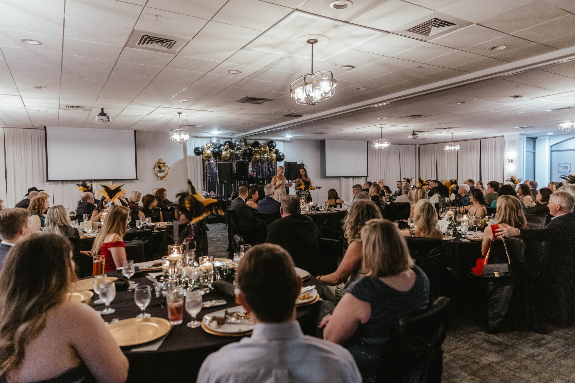 The full ballroom during the program, with guests seated at candlelit tables.