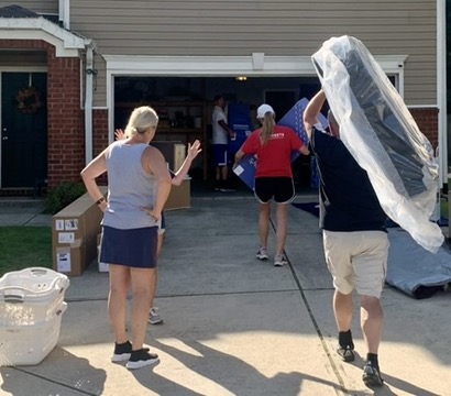 Volunteers moving wrapped furniture and room materials.