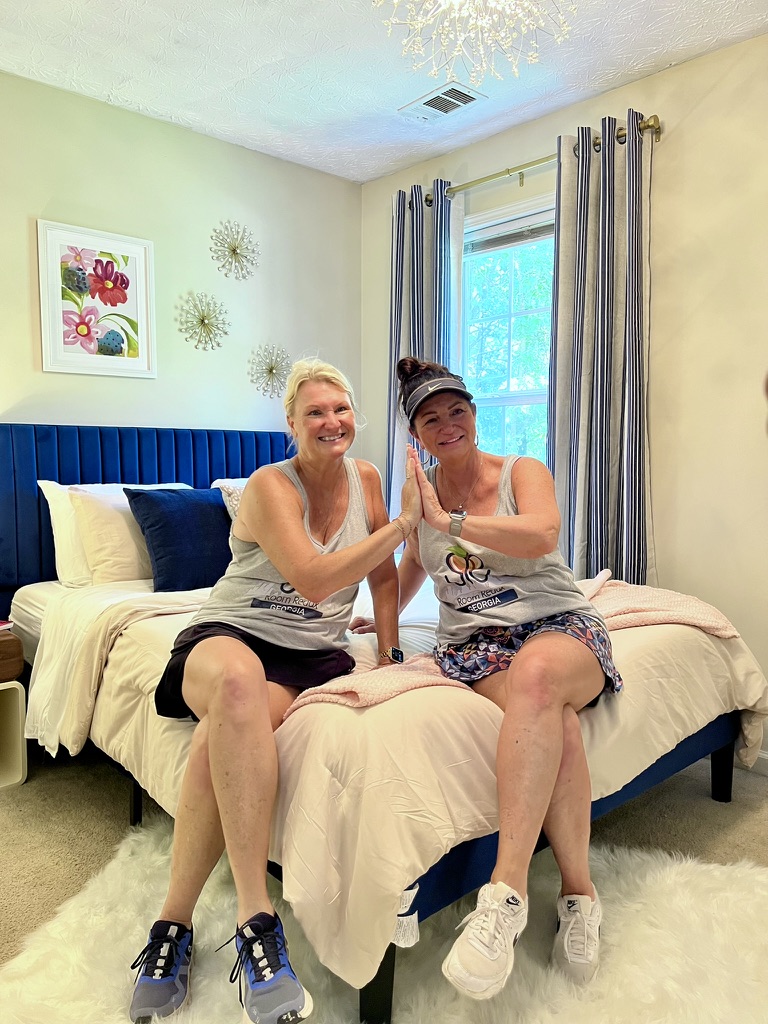 Stephanie Engelerdt and Lisa Lepkofker high-five while sitting on a completed bed during a Room Redux of Georgia transformation.