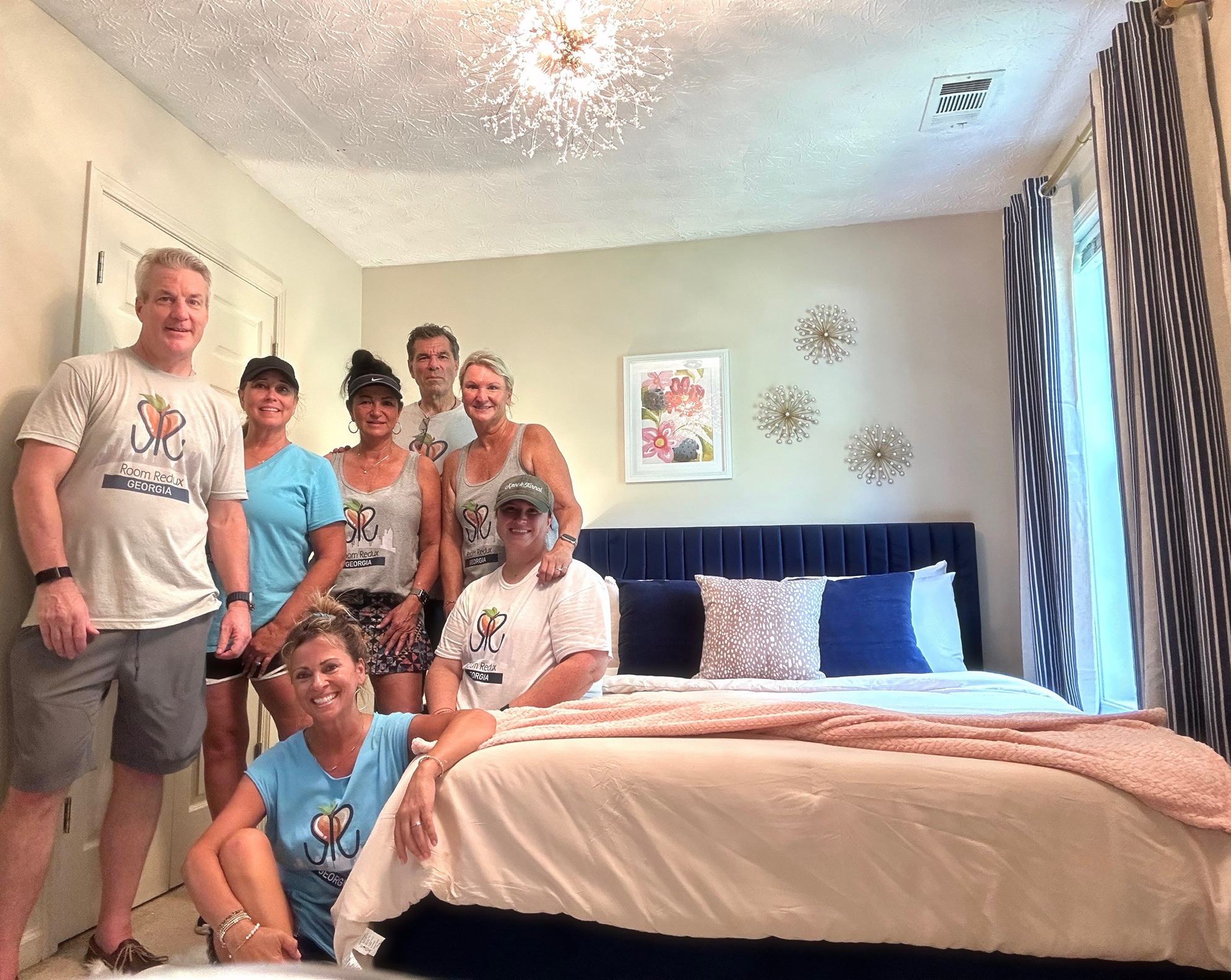 RRGA volunteers gathered inside a completed navy and blush bedroom transformation.