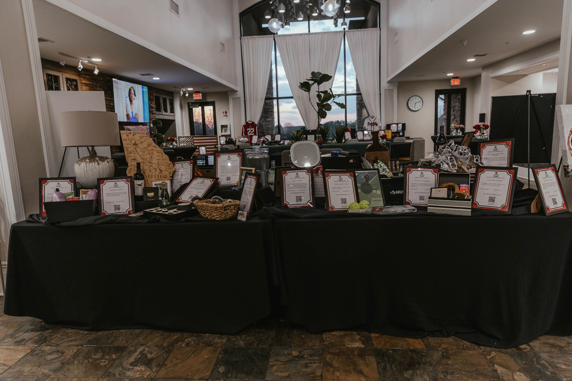 Silent auction tables displaying gift packages and framed certificates at the Lady in Red Gala.