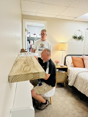 Volunteer installing a custom shelf inside a bedroom.