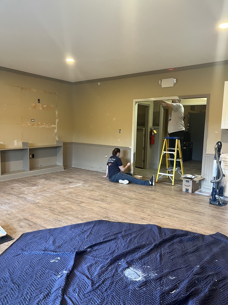 The shared living space before the transformation, with bare walls being patched and painted and drop cloths across the floor.