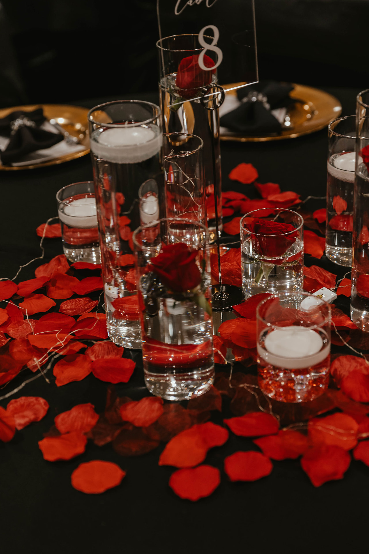 A table centerpiece with red roses, candles and rose petals at the Lady in Red Gala.