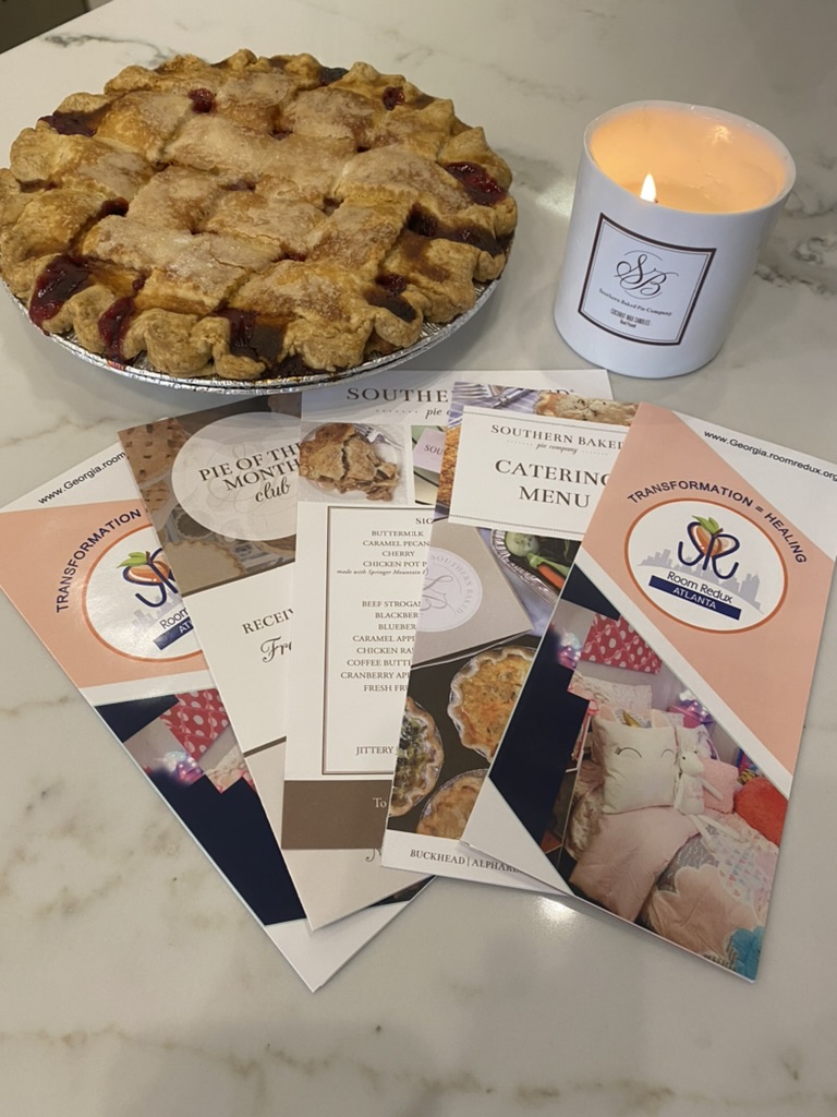 A Southern Baked Pie Company pie, branded candle and co-branded Room Redux of Georgia and Southern Baked Pie Company catering materials on a marble counter.