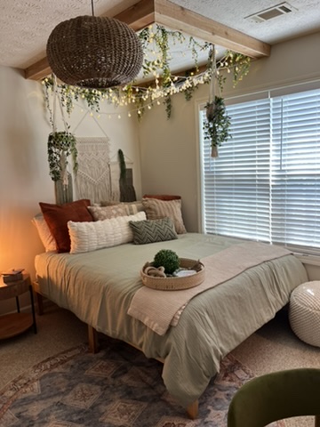 Completed neutral-toned RRGA bedroom with layered bedding, greenery and warm lighting.